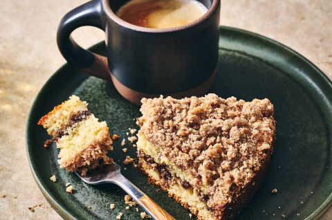 Cinnamon Streusel Coffee Cake on a dark green plate with a cup of coffee - select to zoom