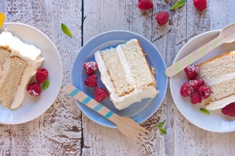 Three slices of Tender White Cake on plates, revealing their double layers of white cake and vanilla frosting.