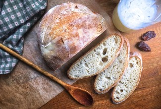 Naturally leavened sourdough bread made with yeast water in place of standard sourdough starter, sliced open and set on a wooden table.
