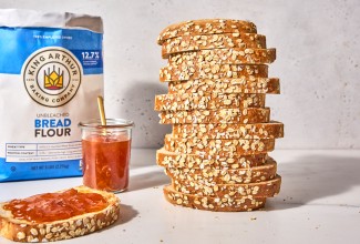 Bag of bread flour behind a sliced loaf of oatmeal sandwich bread