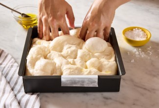 Dimpling focaccia dough in a focaccia pan