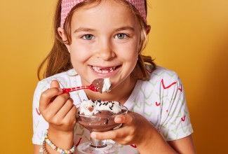 A little girl eating chocolate pudding