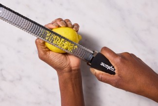 Hands zesting a lemon with a microplane zester