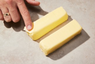 Baker placing their finger on two sticks of cold butter
