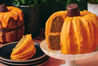 A sliced pumpkin shaped bundt cake showing layers of dark cake and orange frosting.