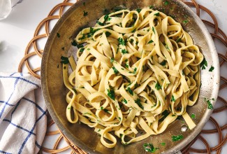 A bowl of gluten free pasta dressed with parmesan and parsley.