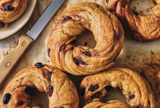 A handful of freshly baked Cinnamon Raisin Bagels on parchment paper seen from above.