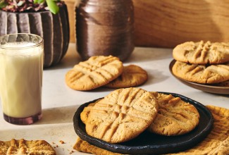 A photograph of Classic Peanut Butter Cookies on a plate with a glass of milk next to it.