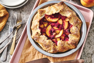 Photograph of Rustic Raspberry-Peach Pie from above with a perfectly browned folded crust around the edges of a vibrant raspberry and peach filling.
