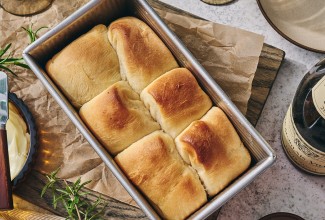 A loaf pan filled with freshly baked Small-Batch Parker House Rolls.
