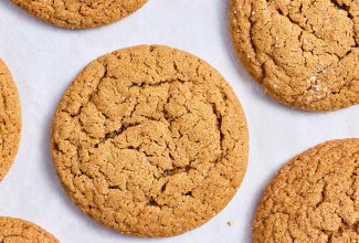 Soft Brown Sugar Cookies laid out on white parchment showing the top of the cookies with a soft cracked top and dark golden hues.