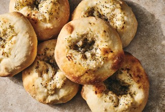 Classic Bialys stacked together with herbs and golden crust on each.