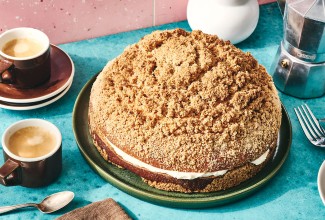 A Cream-Filled Coffee Cake on a dark plate showing a crumb top, cream edge in the middle, and coffee.