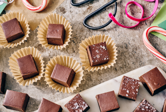 Easy Microwave Fudge cut into neat squares and placed in small paper cups with scissors and ribbon in the shot.