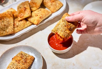 A Homemade Pizza Pocket being dipped in marinara sauce