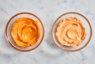 Small bowl of brighter orange frosting next to a small bowl of pale orange frosting 
