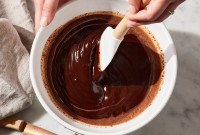Baker using spatula to stir a bowl of ganache