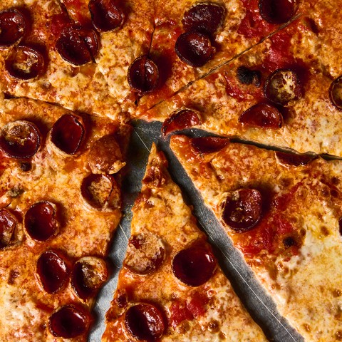 Close up photograph of a pepperoni pizza sliced and seen from above. - select to zoom