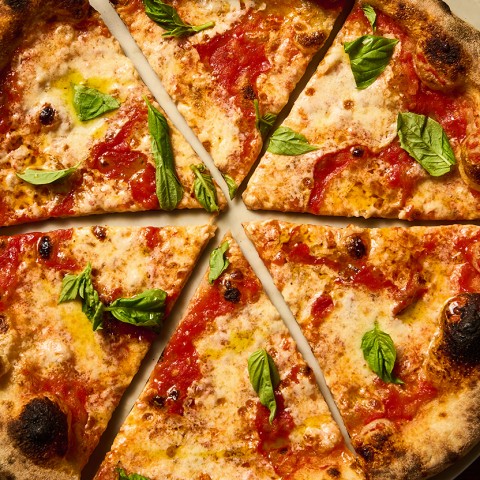 Overhead photograph of a traditional classic pizza showing toppings and a beautifully baked crust. - select to zoom