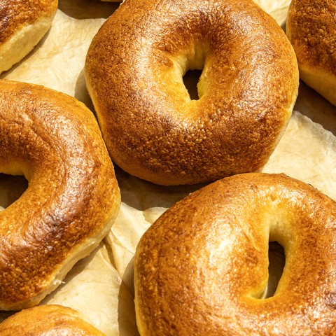 Photograph of golden cooked bagels spread on a baking sheet. - select to zoom