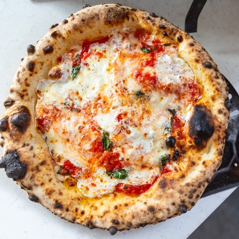 Artisanal woodfired pizza on a peel photographed from above. - select to zoom