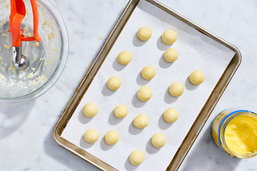 Gulab Jamun rolled into balls on parchment on a baking sheet.