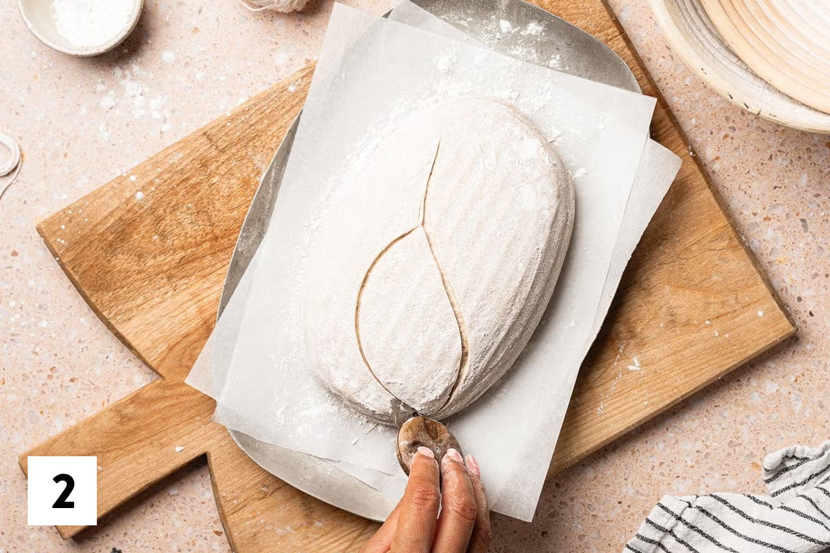 Sourdough bread loaf with part of a leaf design scored into it 