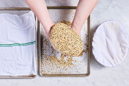 Parmesan Black Pepper Sourdough Bread dough being coated with seasoning before baking.
