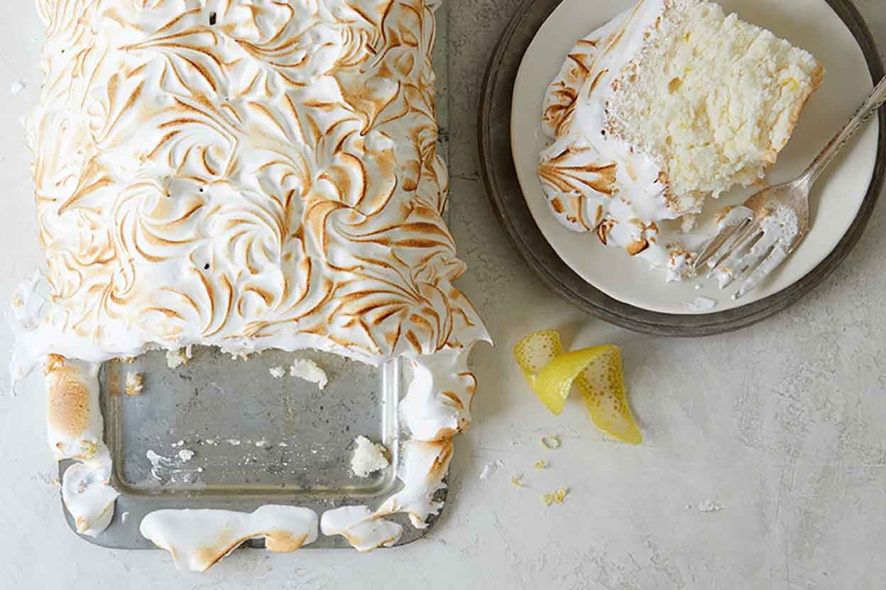 A Lemon Angel Food Cake with Meringue Topping with a slice on a plate