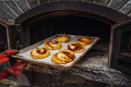 Perfectly Pillowy Cinnamon Rolls being pulled from a wood-fired oven