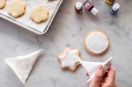 Cornet being used to add pink dots to the surface of an iced cookie