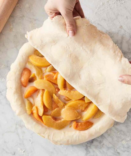 Unbaked peach pie with top crust half on