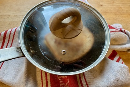 Pan with grilled cheese with a clear lid on it