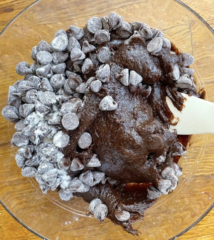 Floured chocolate chips being stirred into brownie batter.