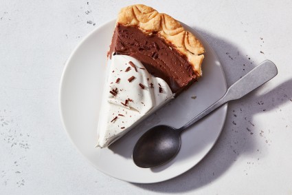 A slice of Chocolate Cream Pie on a plate, topped with whipped cream and chocolate shavings