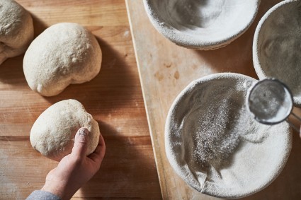 Dusting cloth-lined banneton with flour using a sifter