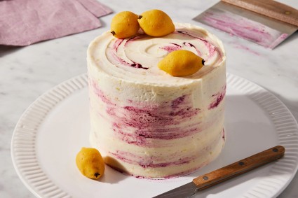 Plate displaying frosted cake with decorative marzipan lemons. 
