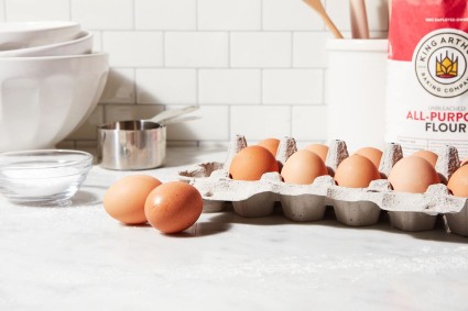A dozen eggs on the kitchen counter next to a bag of King Arthur Flour