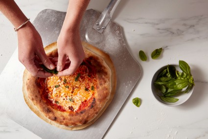 Tearing basil to top a Neapolitan-style pizza