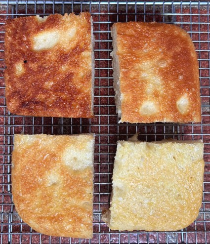Four squares of focaccia, baked in four different pans, turned upside down on a cooling rack to show the difference in color of their bottom crusts.