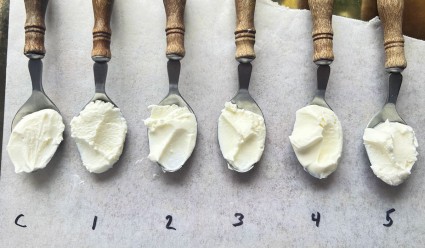Six spoonfuls of creme fraiche lined up on a piece of parchment, showing their identical texture.