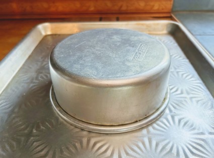 A 6" round cake pan set atop a baking sheet, where it will serve as a pedestal for the upside-down crust as it bakes between two pans.