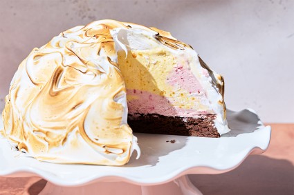 Baked Alaska on a serving tray with a piece taken out of it to show the interior