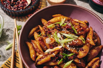A purple tinted bowl filled with hand cut noodles dressed with umami sauce.