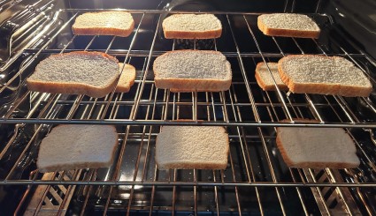 Slices of bread toasting on an oven rack in the oven.