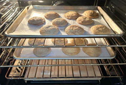 Two half-sheet pans of cookies baking in the oven.