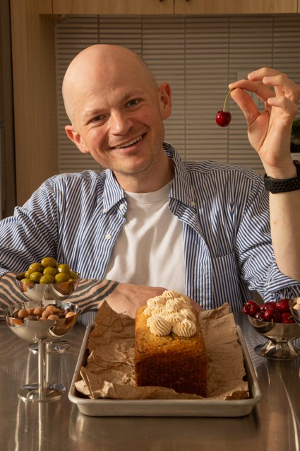 Jordan Smith in front of a loaf cake, holding up a cherry