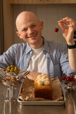 Jordan Smith in front of a loaf cake, holding up a cherry
