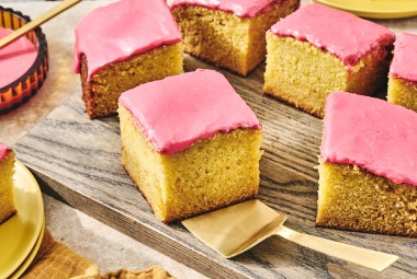 Cranberry-Orange Olive Oil Cake sliced up and arranged on a glass plate with a gold hued serving spatula under one of the golden slices.