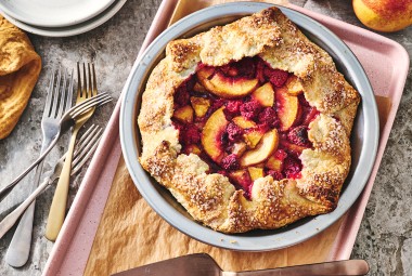 Photograph of Rustic Raspberry-Peach Pie from above with a perfectly browned folded crust around the edges of a vibrant raspberry and peach filling.